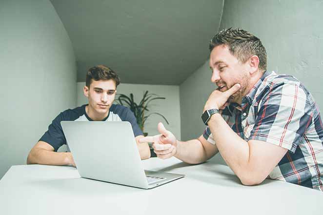 Father and son look at laptop