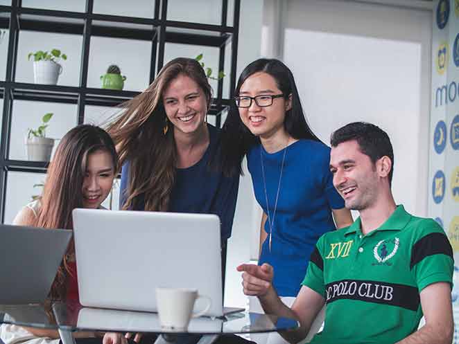 Group of four look at laptop