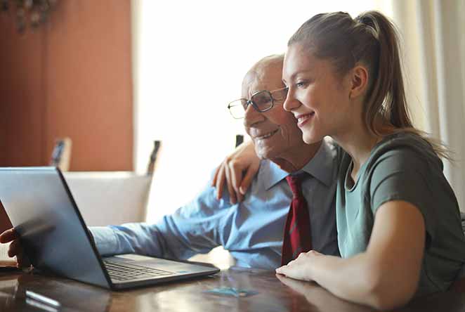 Father and daughter look at laptop