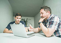 Father and son look at laptop