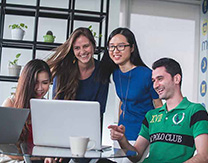 Group of four look at laptop