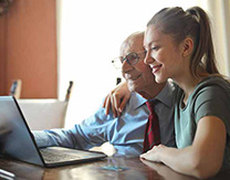 Father and daughter look at laptop